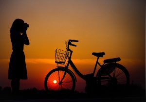 silhouette of woman with camera and bicycle
