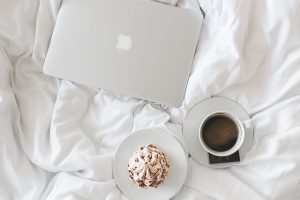 coffee, pastry and laptop on bed