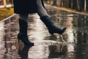 Female legs and women leather boots in the rain