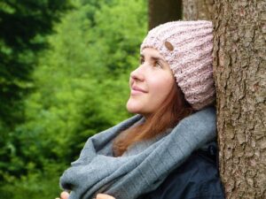 woman leaning against tree in winter clothing